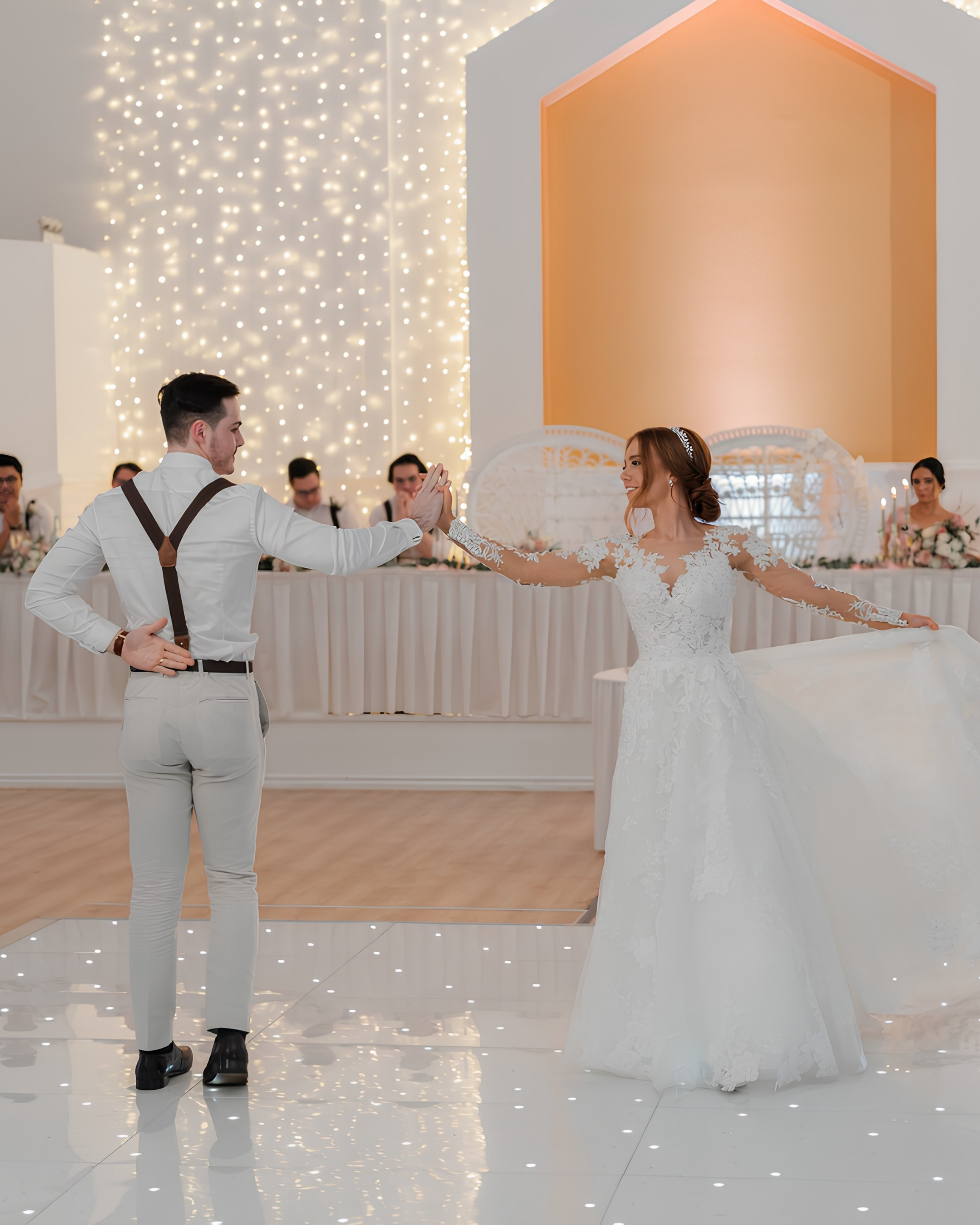 A newlywed couple sharing a joyful first dance beneath sparkling lights
