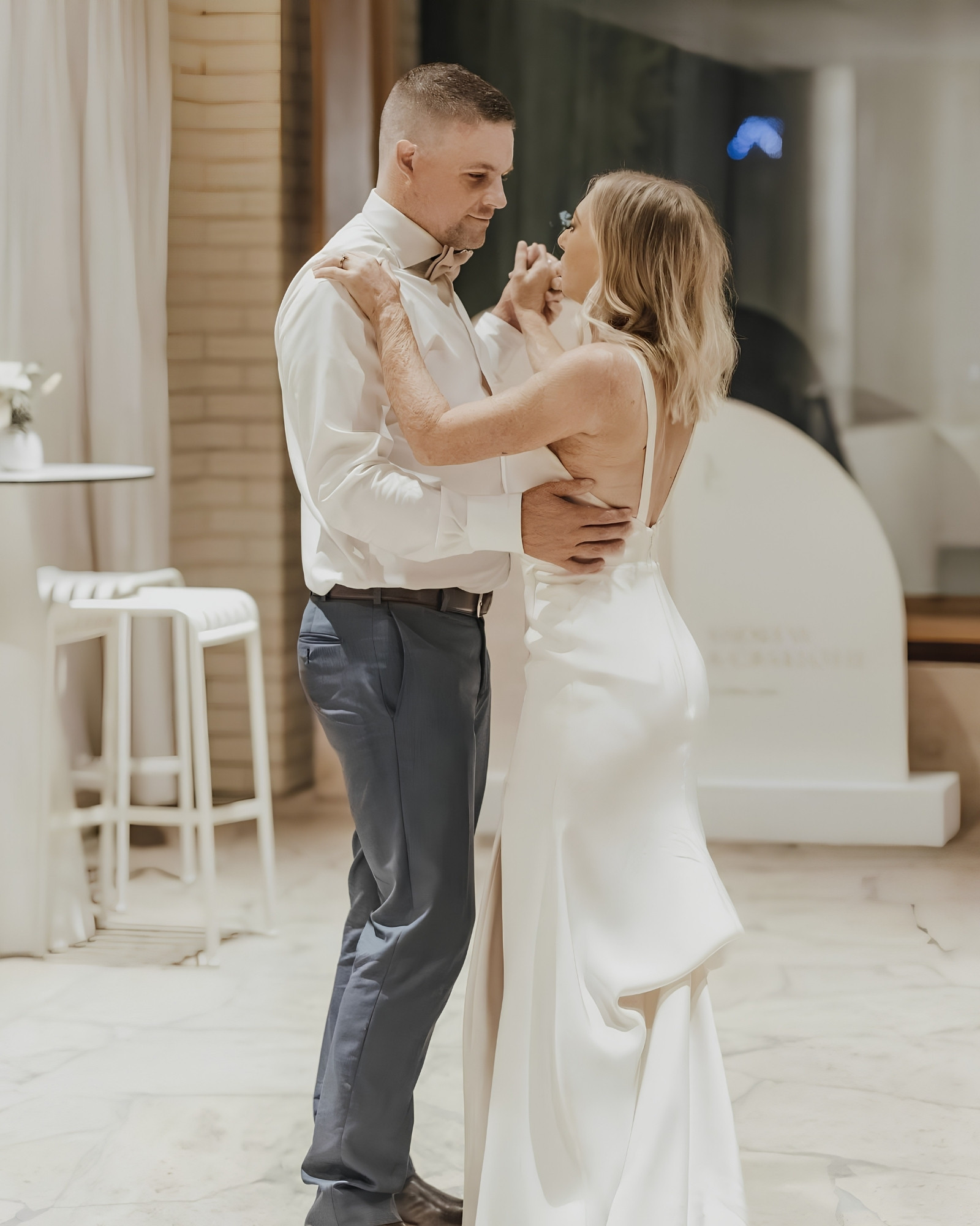 A newlywed couple holding each other closely during their first dance