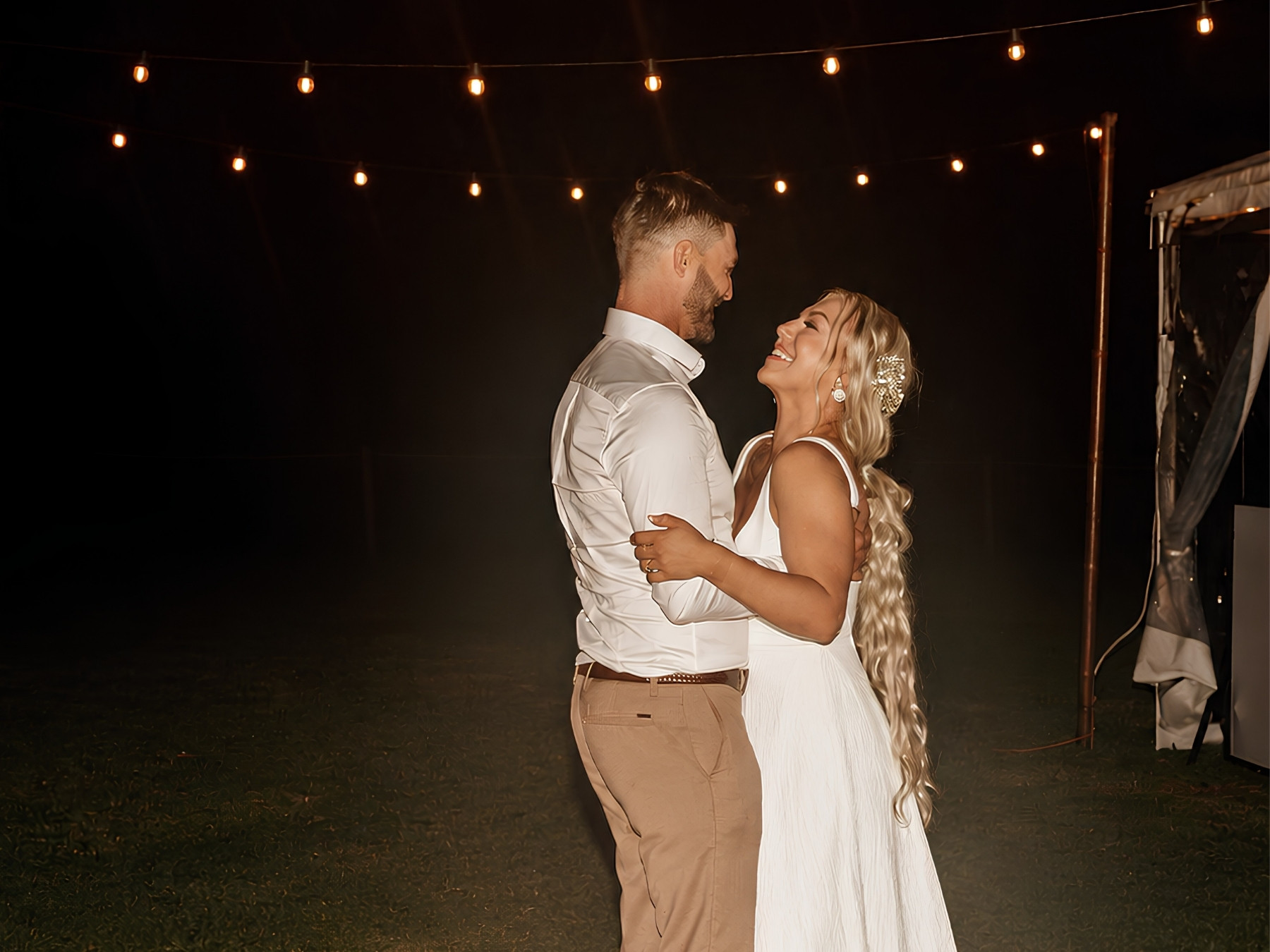 A newlywed couple sharing a quiet moment beneath warm fairy lights