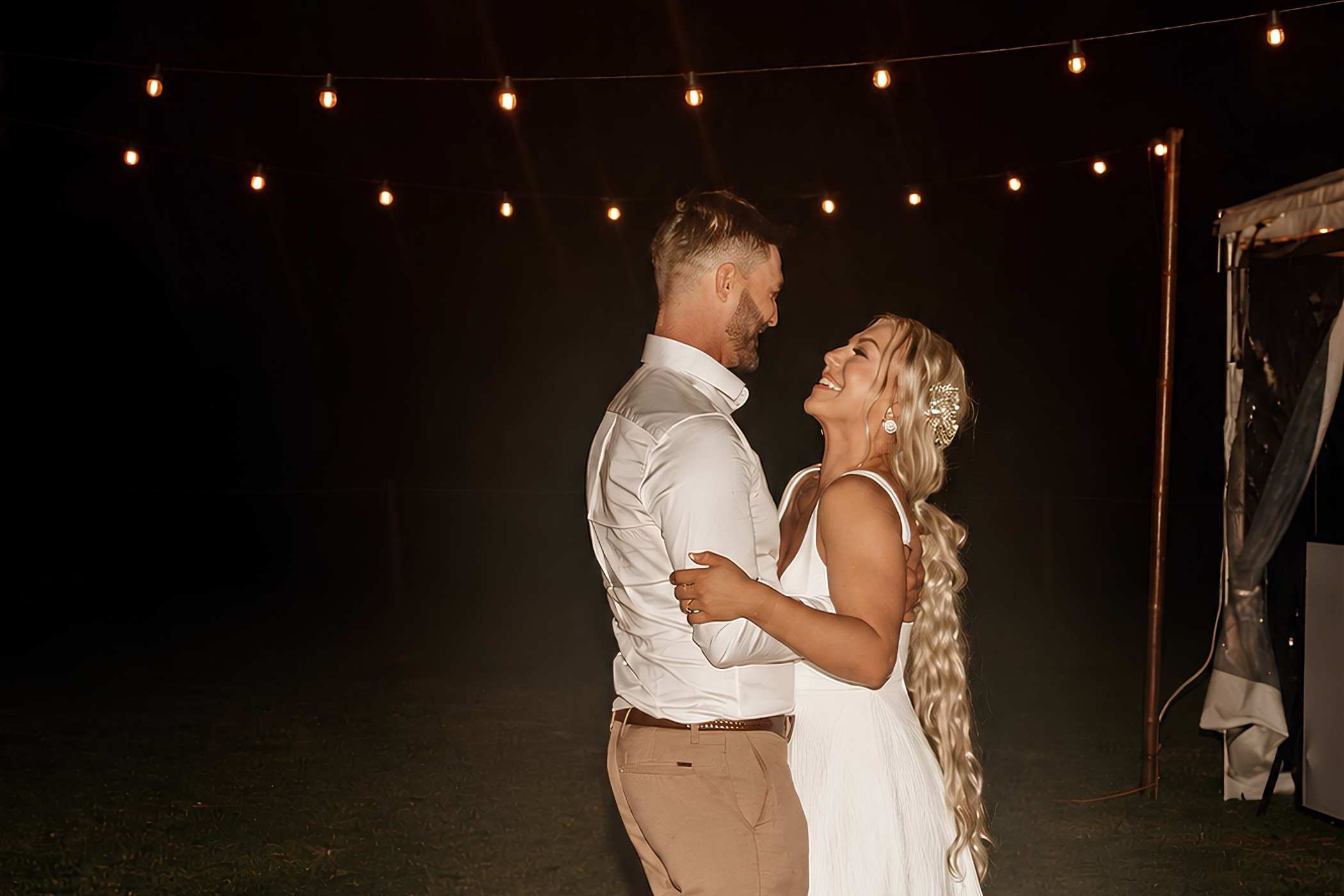 A newlywed couple sharing a quiet moment beneath warm fairy lights