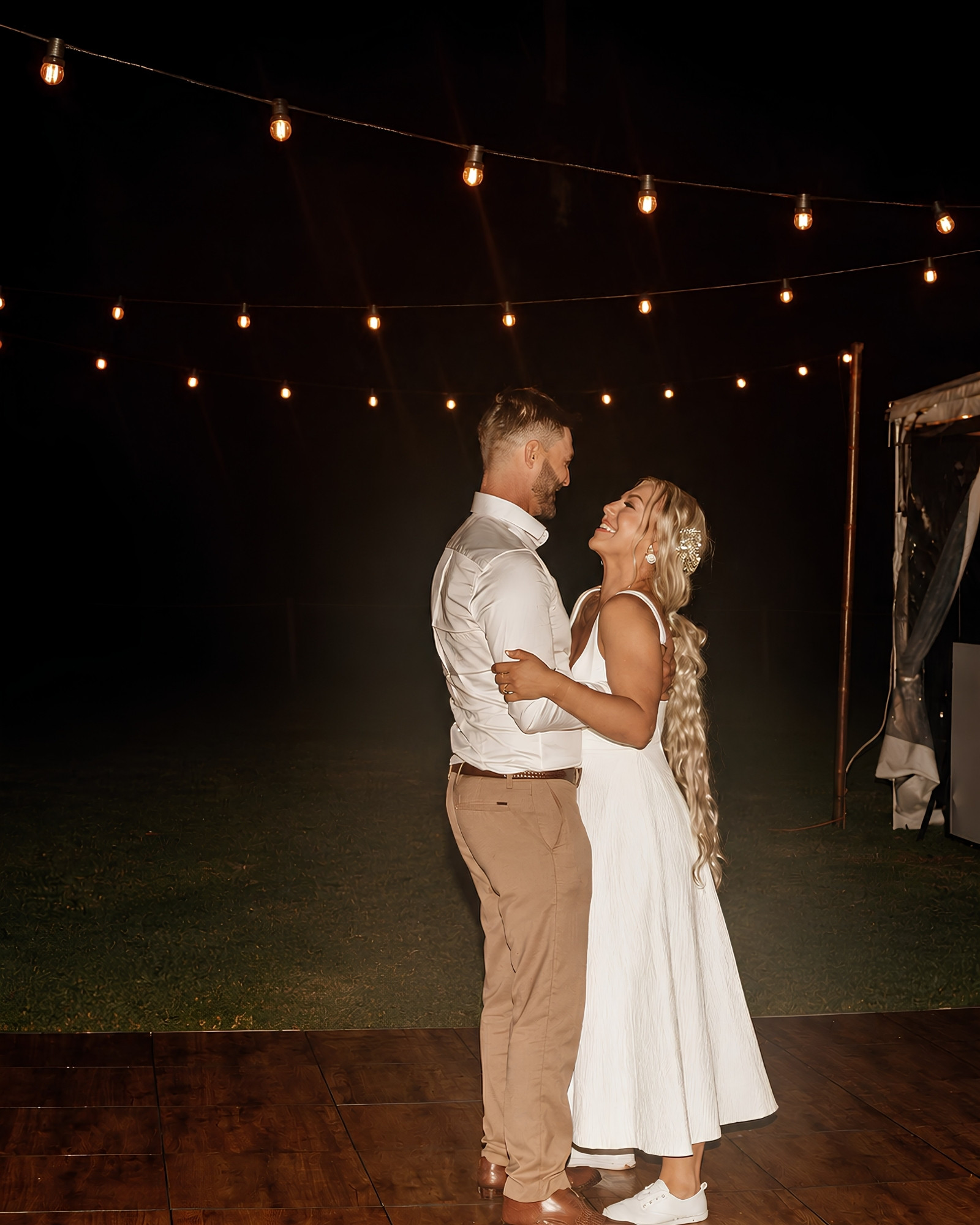 A newlywed couple sharing a quiet moment beneath warm fairy lights